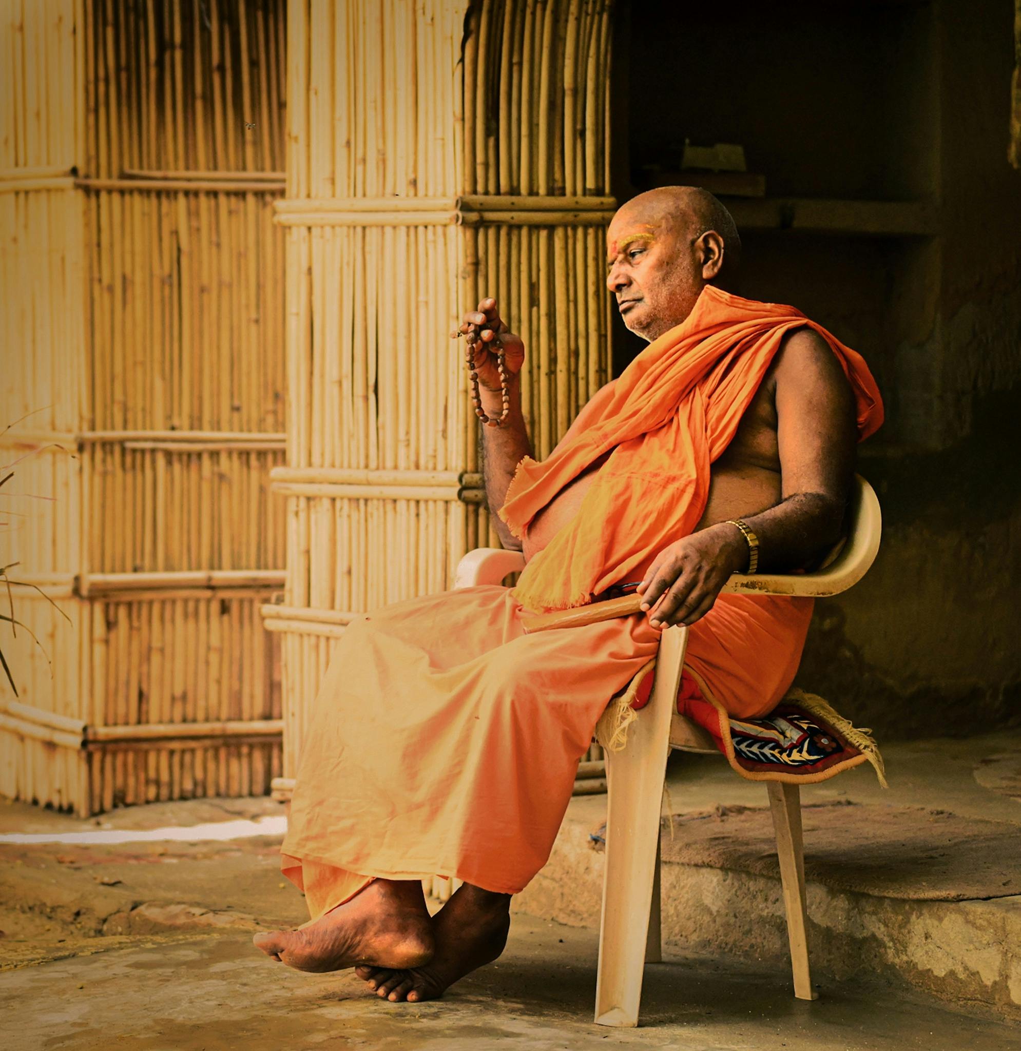A monk in traditional attire meditates peacefully in Mahaban Bangar, India.