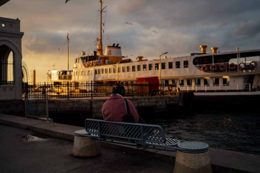A solitary figure sits on a weathered bench, silhouetted against a golden sky—waiting not with desperation, but with presence.