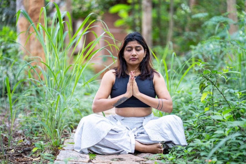 Woman meditating in lush garden setting, finding inner peace.