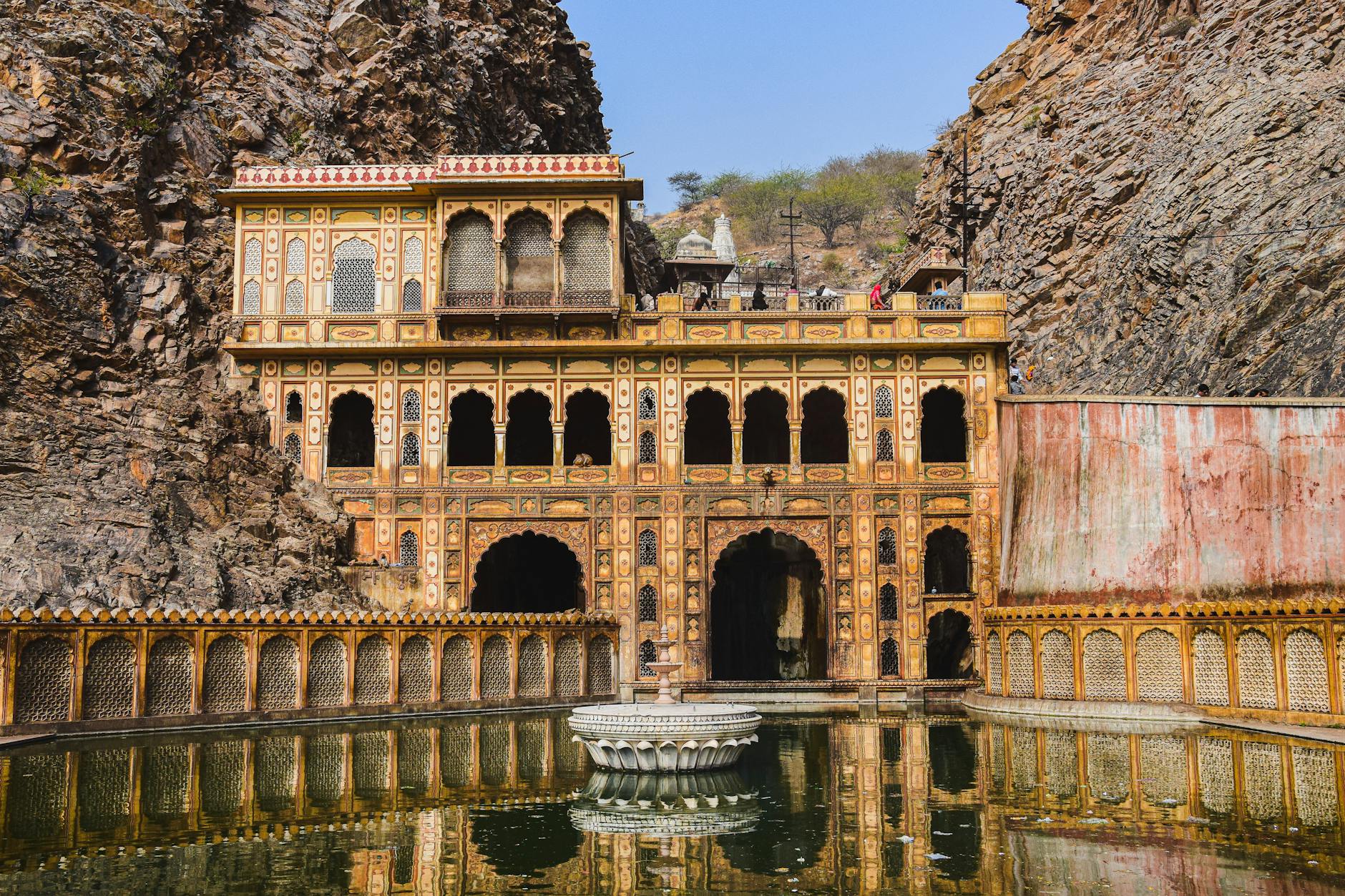 Explore the stunning architecture of Galta Ji Temple set amidst the rocky landscape of Jaipur, India.