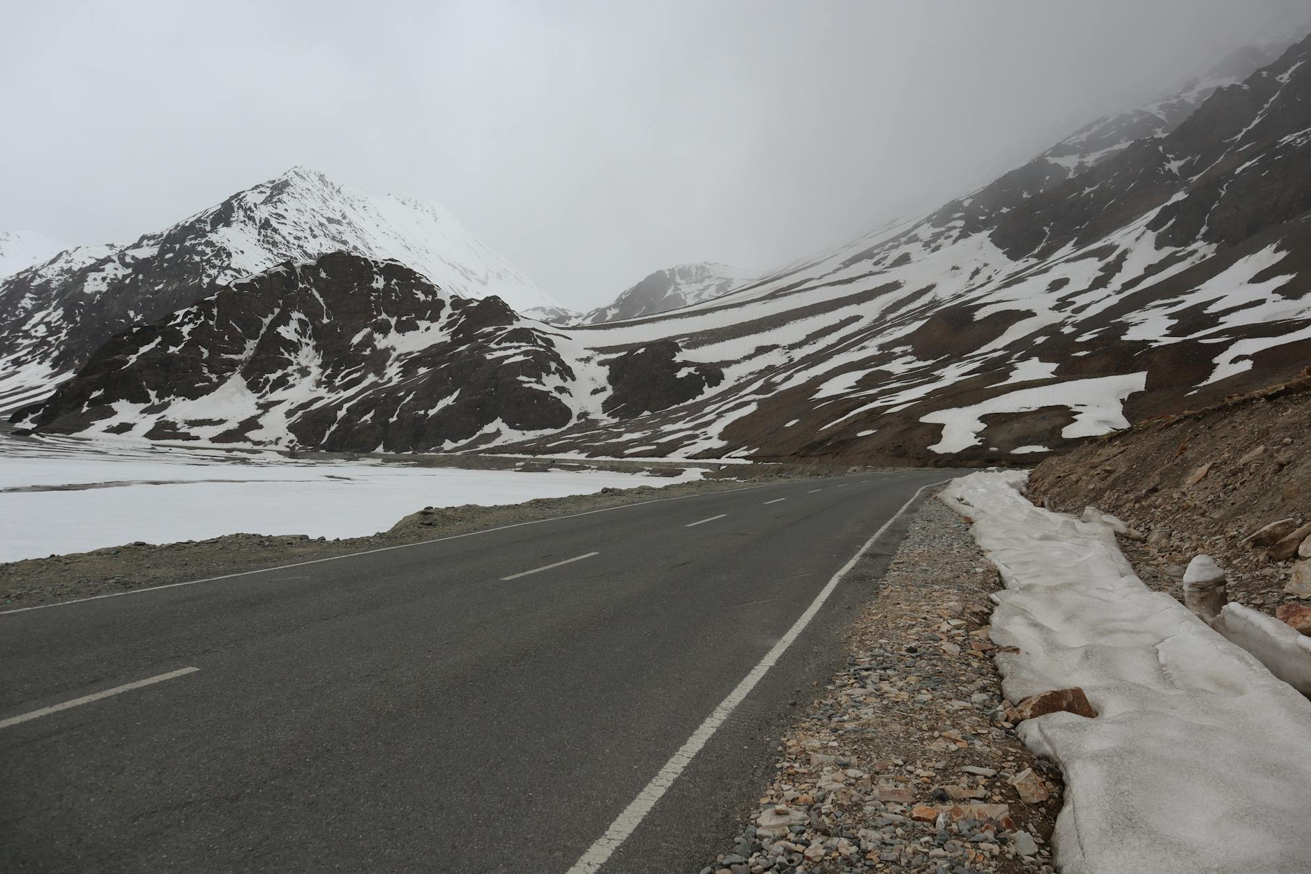 Breathtaking view of a mountain road cutting through snow-dusted peaks in Ladakh, India.