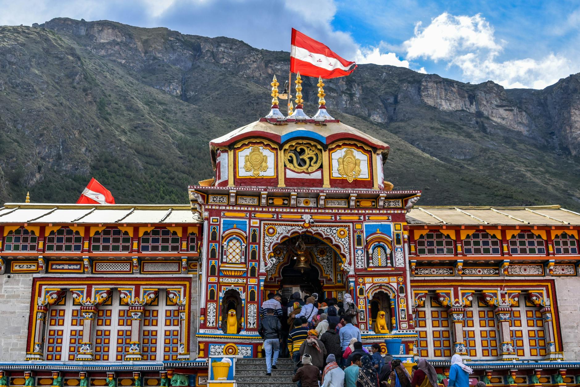lively view of Shree Badrinath Temple with pilgrims gathered around, set against a mountainous backdrop.