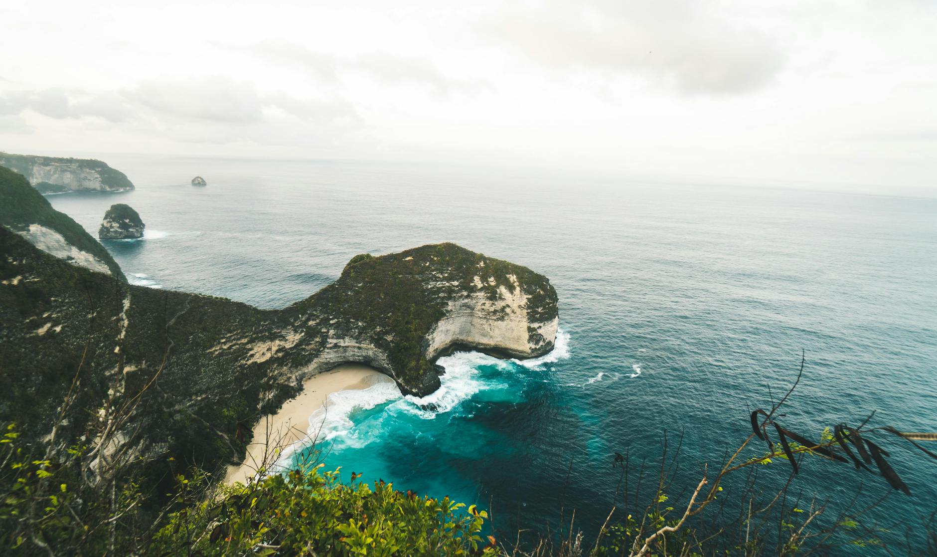 Stunning aerial view over Kelingking Beach on Nusa Penida, showcasing cliffs and turquoise ocean waters.