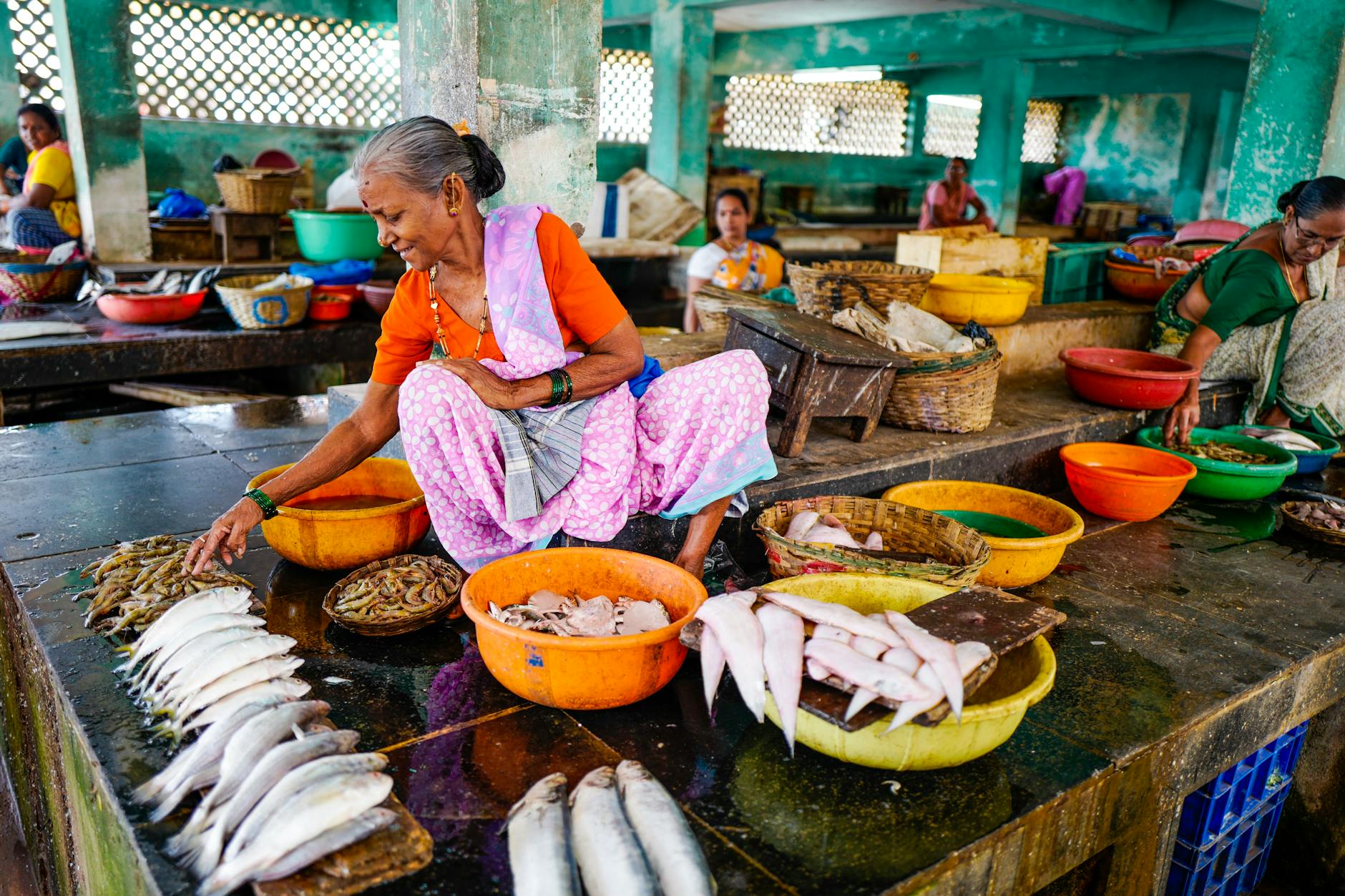 A vibrant Indian fish market with women selling fresh seafood in Bandoli, India.