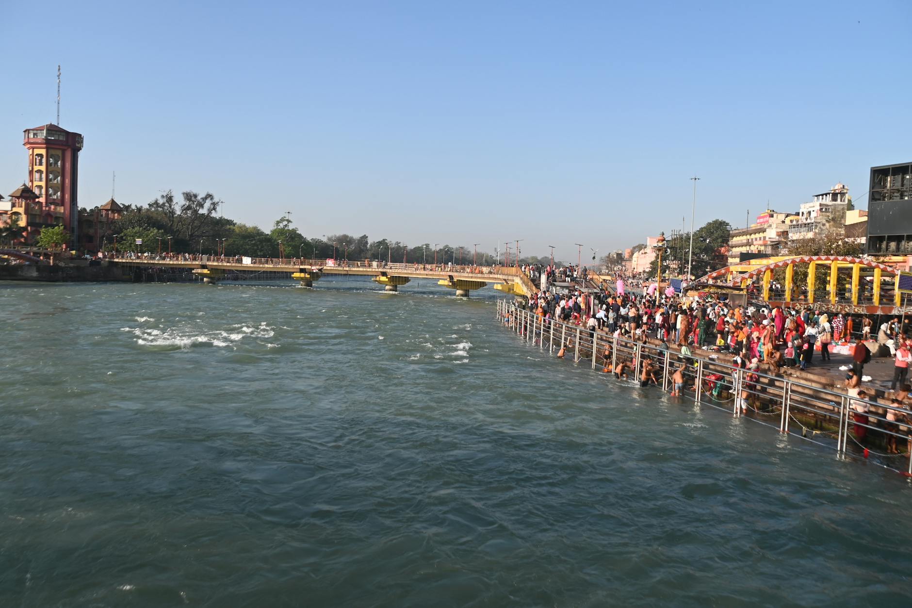 A vibrant scene of people gathered at the riverbank in Haridwar during a lively festival.