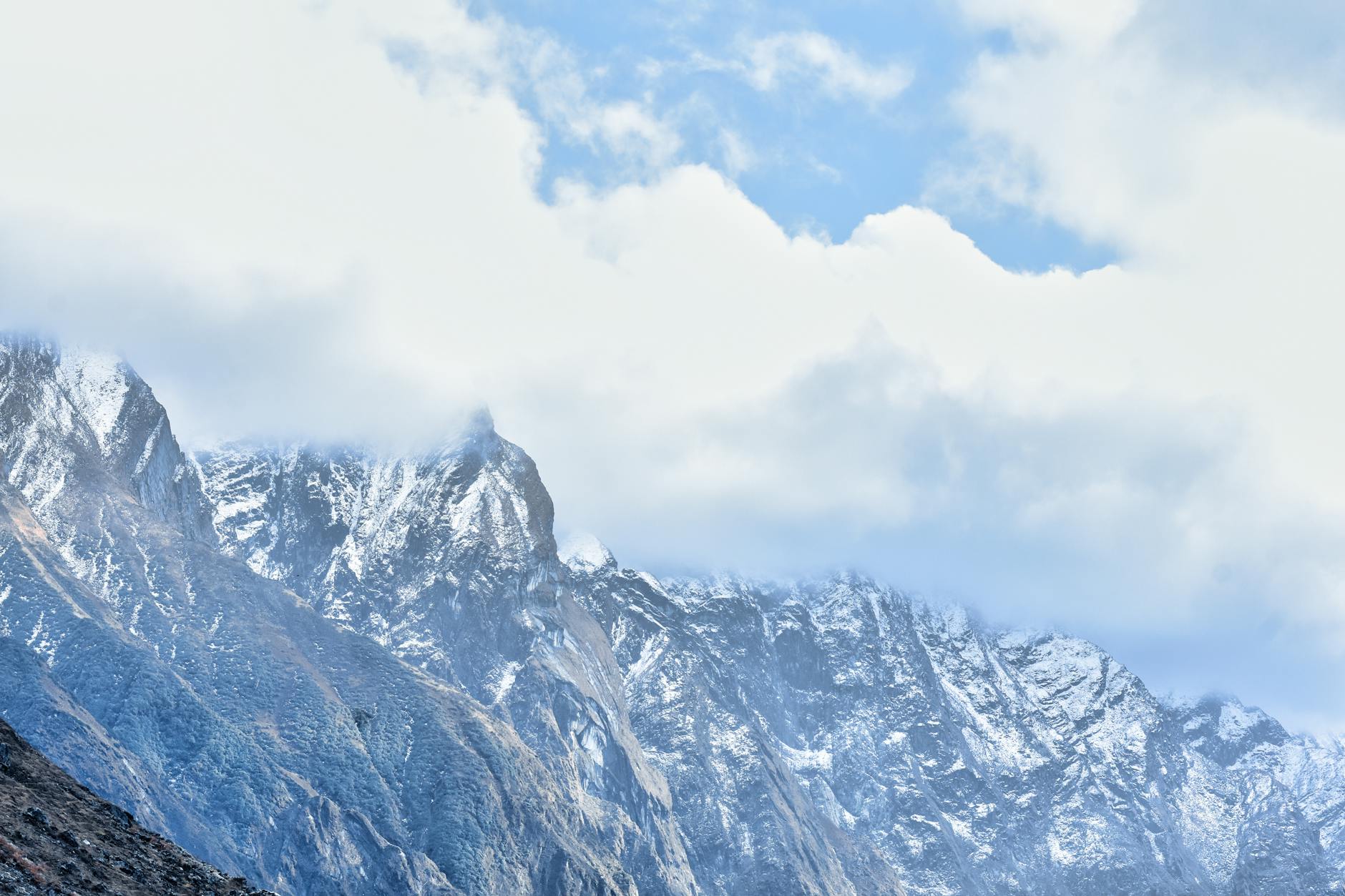 Majestic snow-covered mountains of Kedarnath, India, under a cloudy sky, showcasing natural beauty and rugged terrain.