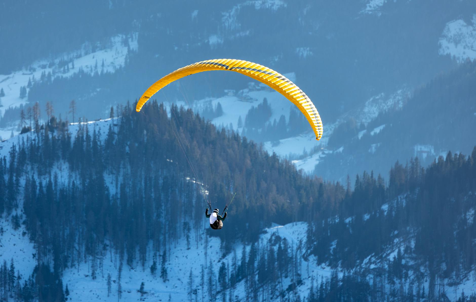 A lone paraglider flies over the scenic Dolomites mountains in Trentino-South Tyrol, Italy, during winter.