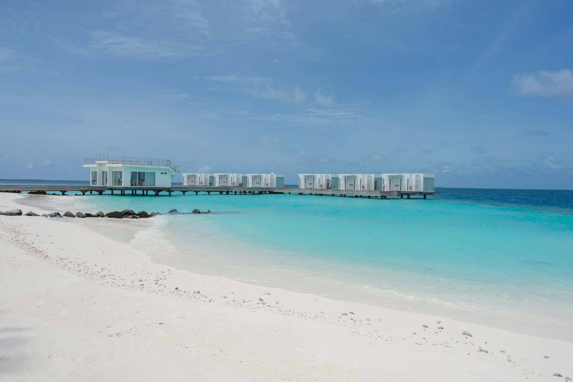 Luxurious overwater villas on a pristine beach with turquoise waters and clear blue skies.