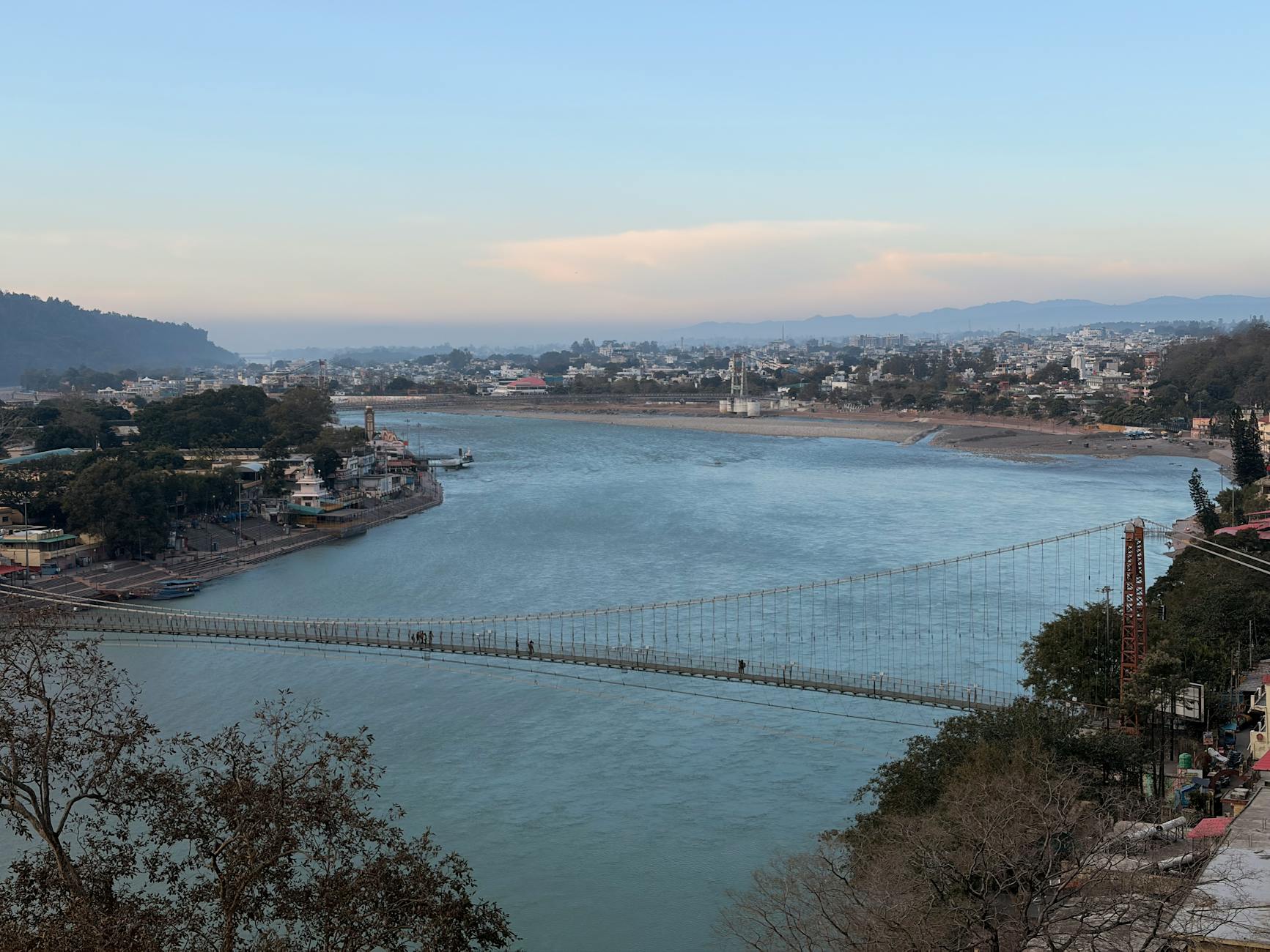 A breathtaking view of the iconic Laxman Jhula bridge in Rishikesh over the Ganges River during daytime.