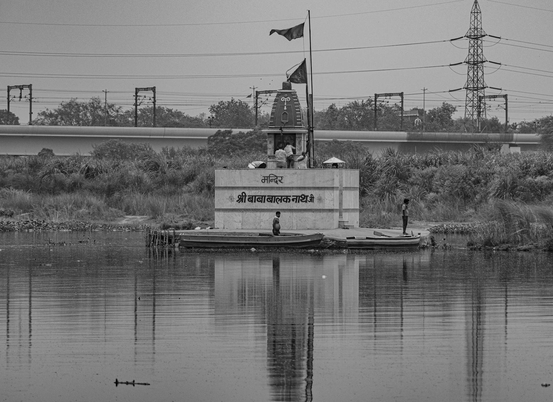 Black and white image of a temple by a lake in New Delhi, India, capturing a serene scene.