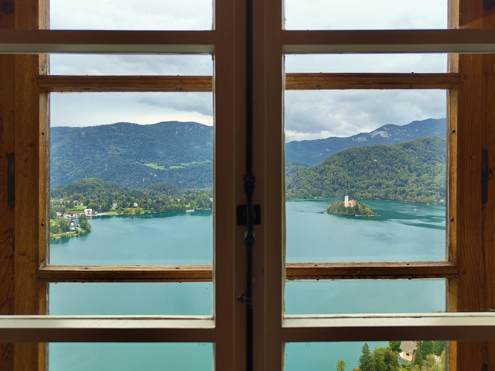 Beautiful view of Lake Bled and its island through a wooden-framed window.