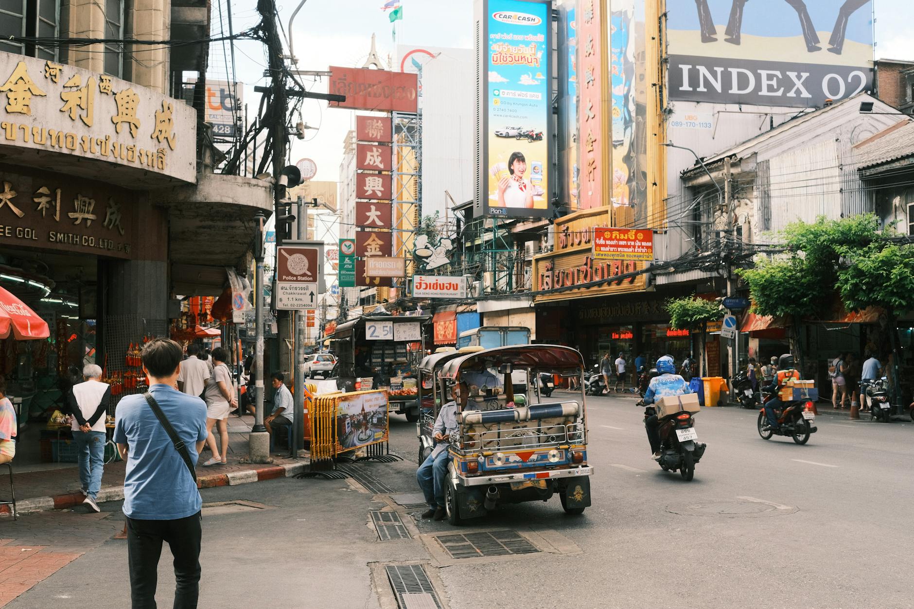Bustling Bangkok Chinatown street scene with tuk-tuks and vibrant signage.