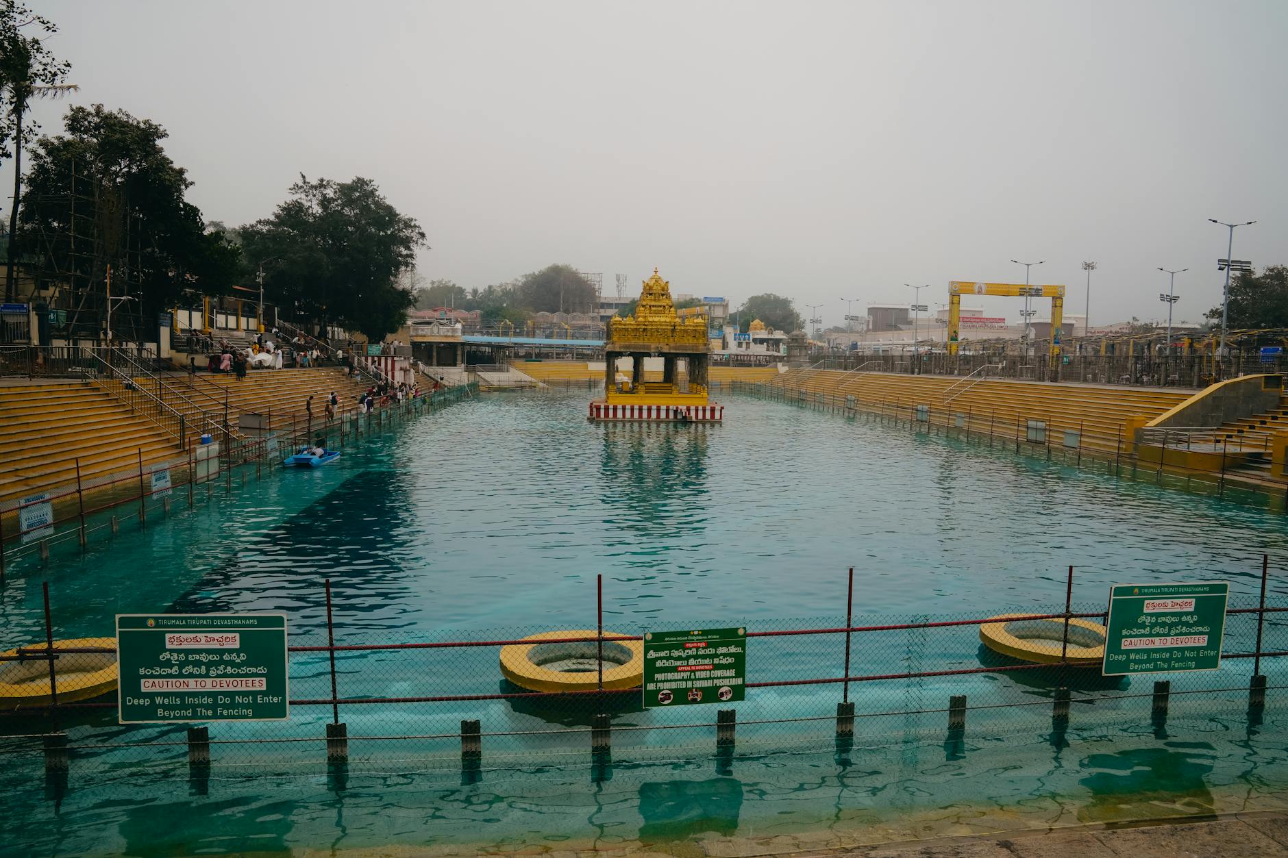 A serene view of the sacred tank at a famous Hindu temple in Tirupati, India, with devotees present.