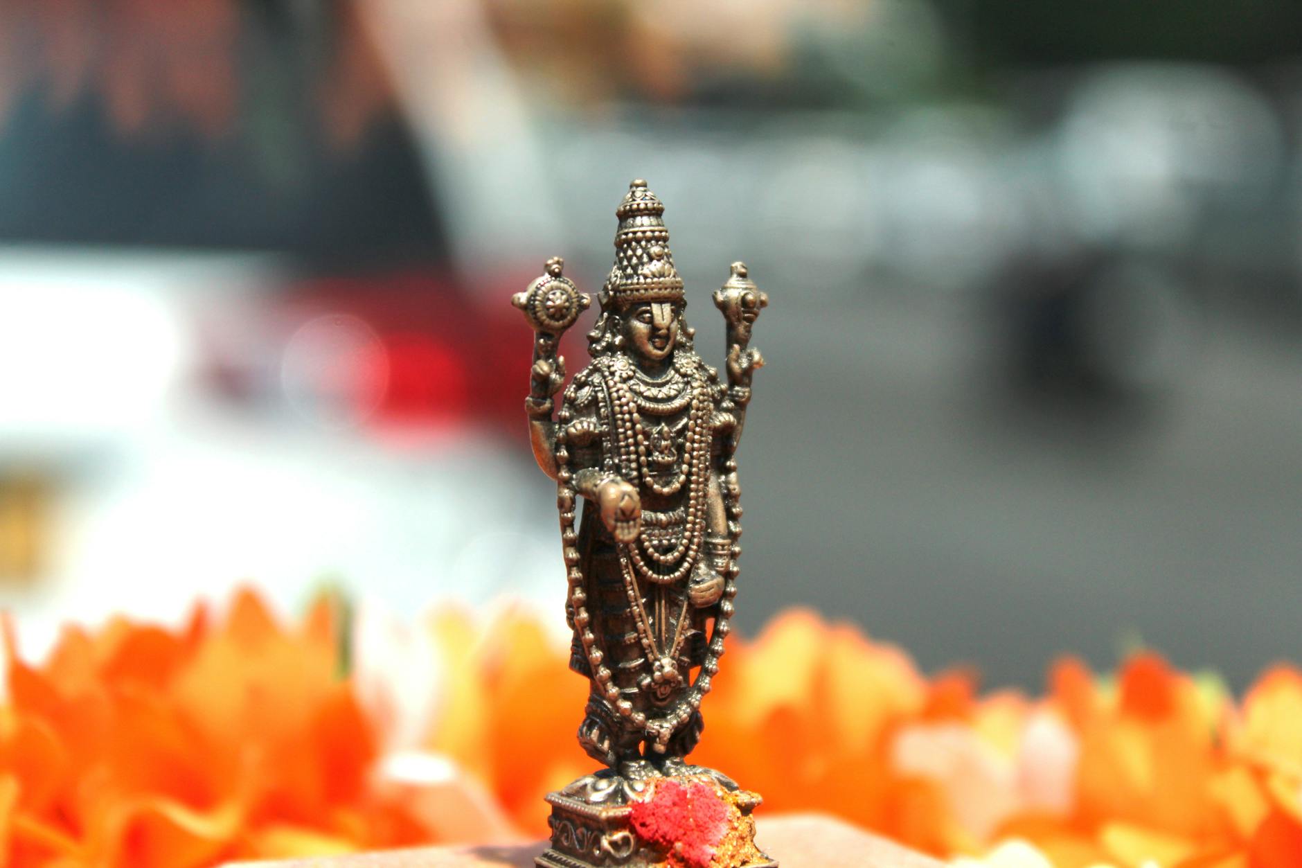 Close-up of a Hindu deity statue with vibrant marigold flowers in Tirupati, India.
