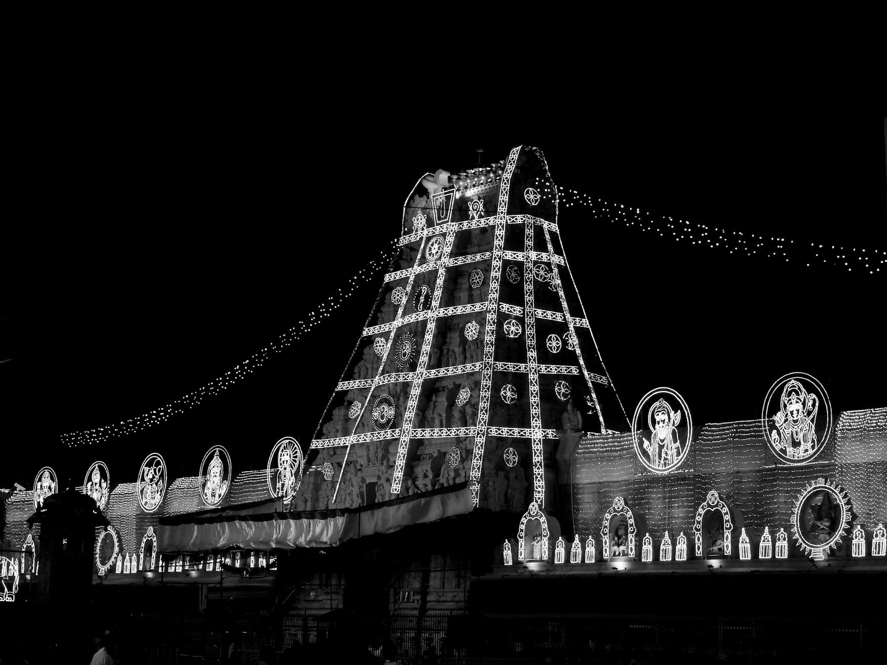 Black and white photo of a building with decorative lights at night, capturing a festive atmosphere.