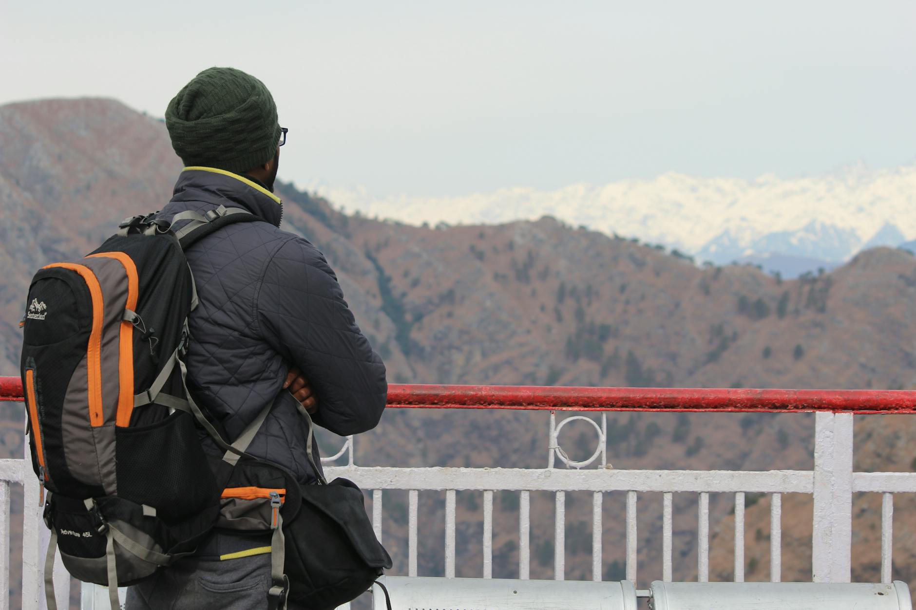 A backpacker enjoys a scenic view of the snowy mountains from Vaishno Devi.