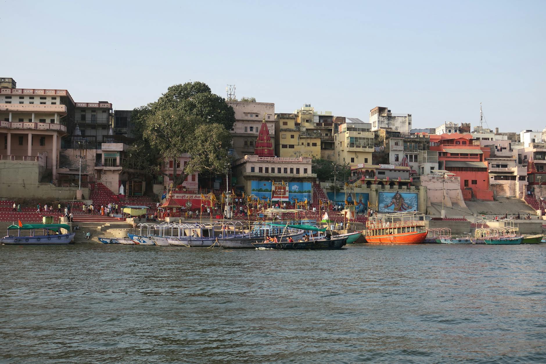 Vibrant scene of Varanasi's ghats with boats on the Ganges River, showcasing cultural and historical landmarks.