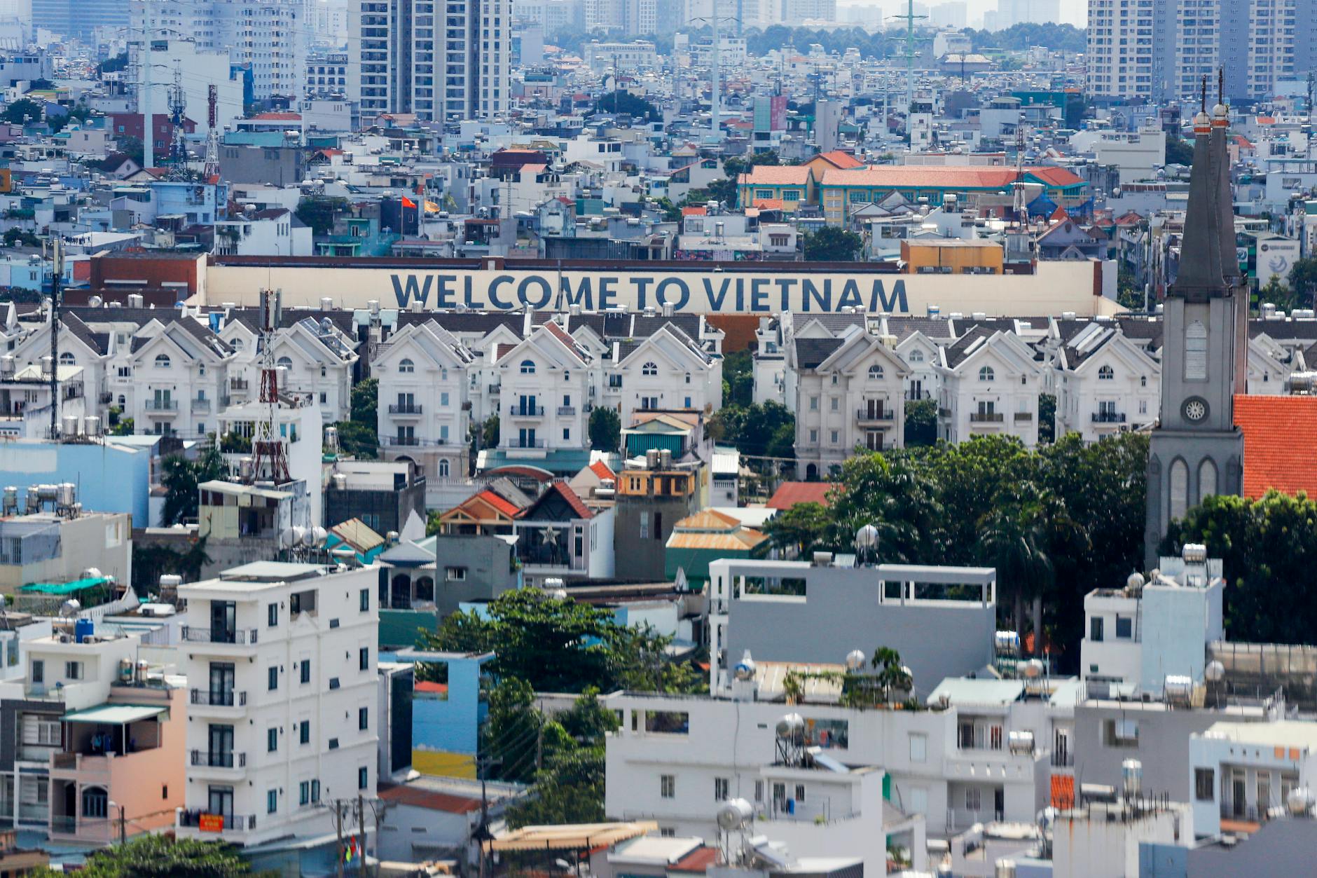 A vibrant aerial view of Ho Chi Minh City featuring the iconic 'Welcome to Vietnam' sign among buildings.